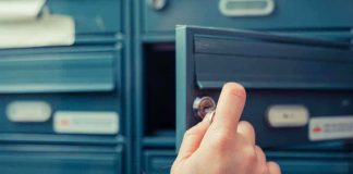A hand holding a key, opening a blue mailbox drawer