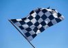 A checkered flag waving against a clear blue sky