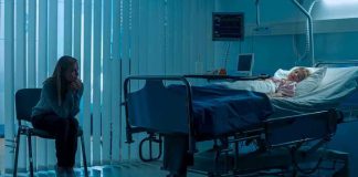 Woman sitting beside hospital bed at night.