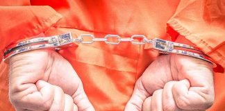 Hands in handcuffs wearing an orange jumpsuit