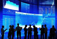 Silhouetted business professionals in front of digital stock market displays