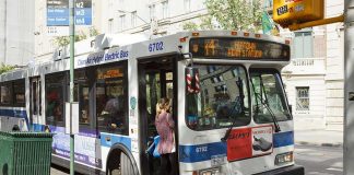 A woman boarding a clean air hybrid electric bus at a city stop