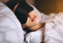 Woman sleeping with a black sleep mask in a cozy bed