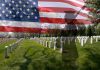 Families’ Bold Demand to Trump: “Finish Iran Job!” A military cemetery with white gravestones and an American flag overlay, featuring a soldier silhouette