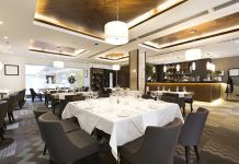 Interior of a modern restaurant with elegantly set tables and a bar area