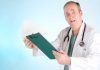 A doctor in a white coat looking surprised while holding a clipboard