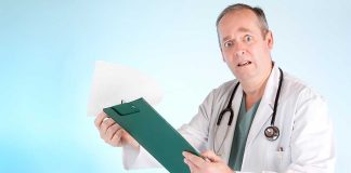 A doctor in a white coat looking surprised while holding a clipboard