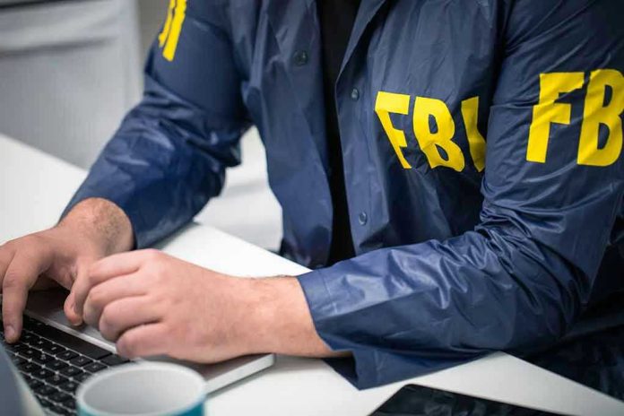 Person in FBI jacket typing on a laptop.