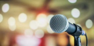 AI Singer Hijacks iTunes Top 100 Microphone with blurred lights in the background.