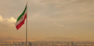 Iran Faces Total Destruction? Trump’s Final Warning Looms Iranian flag waving over a city skyline with mountains in the background