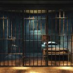 Empty prison cell with metal bars and bed.