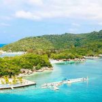 Serial Killer in Paradise? Chilling Clues Emerge Tropical beach with docks and lush green hills.