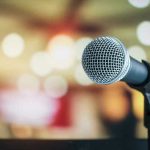 MUSIC SCAM: AI Stealing Musicians’ Royalties Microphone with blurred lights in the background.