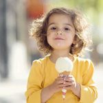 Scary Impact: Junk Food Alters Child Brains A young child with curly hair holding an ice cream cone outdoors
