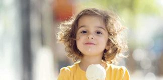 Scary Impact: Junk Food Alters Child Brains A young child with curly hair holding an ice cream cone outdoors
