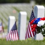Massive Flag Tribute: Arlington’s Hidden Ceremony American flags and flowers placed at graves in a cemetery