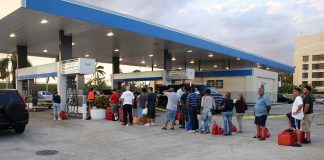 People waiting in line at a gas station with fuel containers
