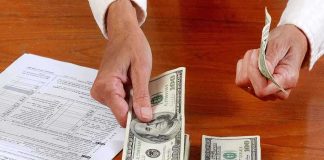 California’s Unprecedented 100% Tax Standoff Sparks Legal Chaos Hands counting cash and reviewing financial documents on a wooden table