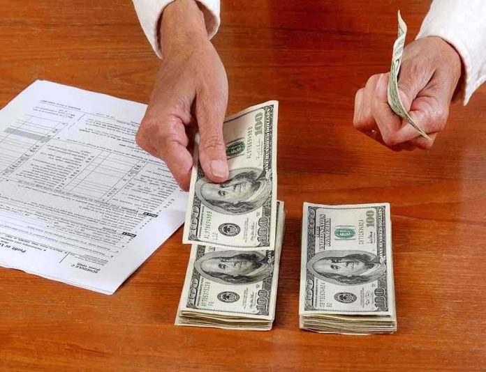shutterstock_97412618 Hands counting cash and reviewing financial documents on a wooden table