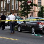 Police and crime scene tape on city street.
