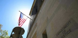 Mass Purge Looms Inside Washington American flag at Department of Justice building exterior.