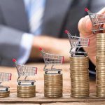 Inflation Spike Shocks Wall Street Mini shopping carts on stacks of coins, business background.