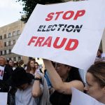 Power Grab? Trump Empties Election Watchdog People holding Stop Election Fraud protest signs.
