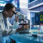 Harvard Finds Missing Metal In Diseased Brains Scientist using a microscope in a modern laboratory