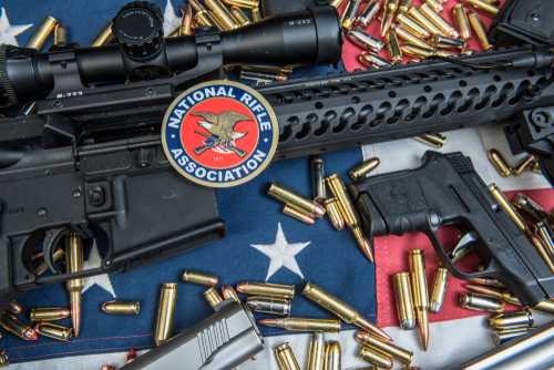 shutterstock_1047043738 A rifle and handgun surrounded by ammunition on an American flag