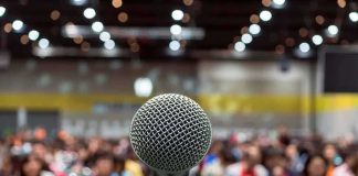 Microphone on stage facing a blurred audience