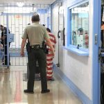 Corrections officers escort an inmate in a jail hallway