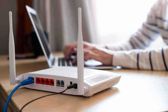 shutterstock_1807512106 Wi‑Fi router on desk with person typing on laptop