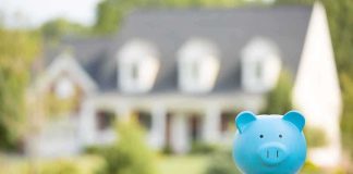Billionaire Cash Hijacks Baby Accounts? A blue piggy bank in front of a blurred house and greenery