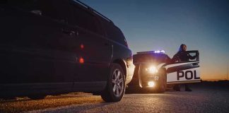 Golf To Handcuffs: Tony Romo Showdown Police officer stands by patrol car during traffic stop at dusk