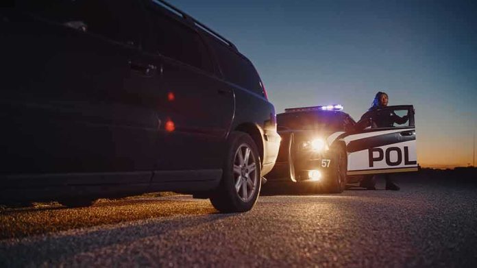 Police officer stands by patrol car during traffic stop at dusk