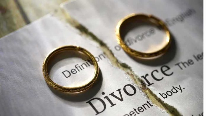 shutterstock_2273572759-3-1- Two wedding rings placed on a torn page with the word 'Divorce'