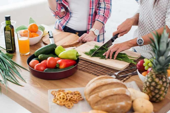 Hands chopping fresh herbs on a cutting board beside assorted produce