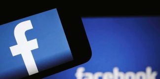 Facebook logo on a smartphone with blurred Facebook screen behind