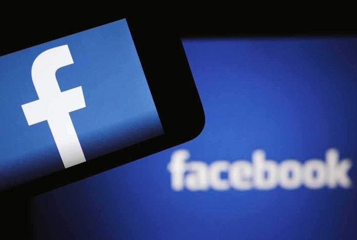 shutterstock_1099603640 Facebook logo on a smartphone with blurred Facebook screen behind