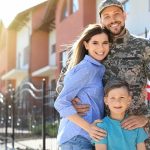 Military family posing together outside a suburban home