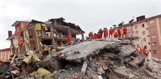 Bodies Rising Fast — The Search Doesn’t End Rescue workers in orange uniforms on a collapsed building site after an earthquake