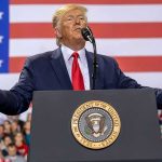 Nuclear Gamble: Trump Teases Kim Showdown speaker at podium with U.S. flag backdrop