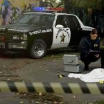 FBI agents examine a covered body at a taped-off crime scene