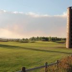 Brick silo beside a golf course at sunset
