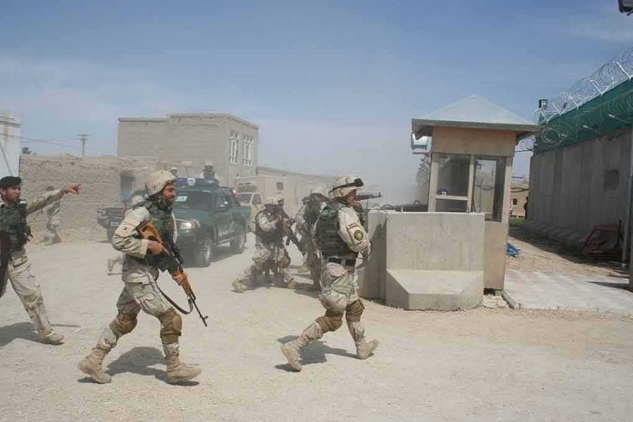 Soldiers in desert uniforms run past a checkpoint amid dust