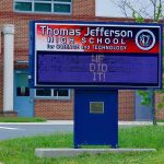Electronic school marquee in front of a brick high school
