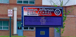 Electronic school marquee in front of a brick high school