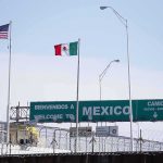 Border crossing with U.S. and Mexico flags and a sign welcoming to Mexico