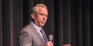 man in a suit speaking into a microphone on stage