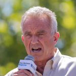 man speaking into a microphone outdoors